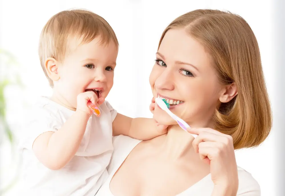 Mother and baby brushing teeth to avoid tooth decay