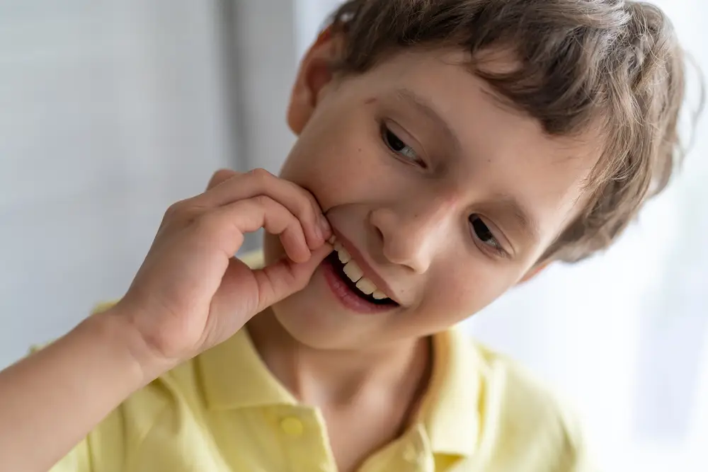 boy wiggling loose baby tooth